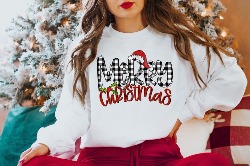 May include: White sweatshirt with a black and white buffalo plaid "Merry Christmas" graphic with a red Santa hat on top of the "M".