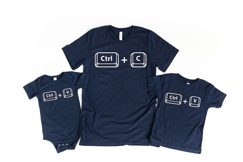 May include: Three navy blue t-shirts with white text and images of computer keys. The largest shirt says "Ctrl + C", the medium shirt says "Ctrl + V", and the smallest shirt says "Ctrl + V".