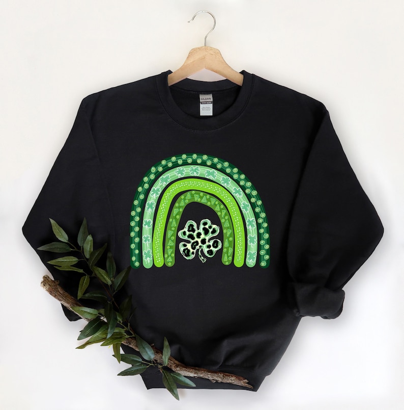 May include: Black sweatshirt with a green shamrock rainbow design. The rainbow is made up of three green arches with shamrock patterns.