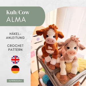 Könnte beinhalten: Zwei gehäkelte Kuh-Stofftiere, eines in Braun-Weiß und eines in Hellbraun-Weiß, mit großen schwarzen Augen und strukturiertem Garn. Das Bild enthält den Text Kuh/Cow ALMA, HÄKEL-ANLEITUNG, CROCHET PATTERN sowie Symbole der britischen und deutschen Flagge.