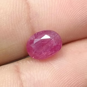 Puede incluir: Una piedra preciosa de rubí ovalada de color rosa vibrante con un corte facetado.