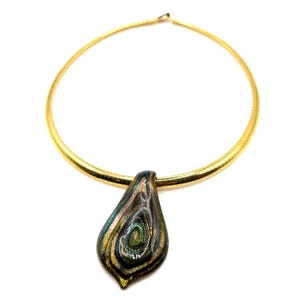 May include: A gold-toned necklace with a teardrop-shaped pendant. The pendant features a swirling pattern of green, gold, and brown colors. The necklace has a ribbed design and a simple clasp.