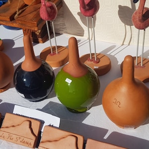 Peut inclure: Une collection de gourdes en céramique peintes à la main dans différentes couleurs, dont le brun, le vert et le bleu. Les gourdes sont exposées sur une table blanche avec des figurines de flamants roses.