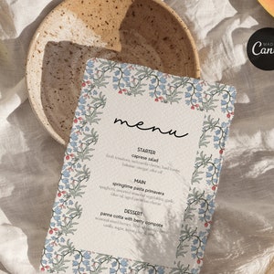 May include: A floral patterned menu with the word "menu" written in cursive at the top. The menu lists the following items: Starter - Caprese Salad, Main - Springtime Pasta Primavera, Dessert - Panna Cotta with Berry Compote. The menu also includes the text "Made in Canva" and "C&f".