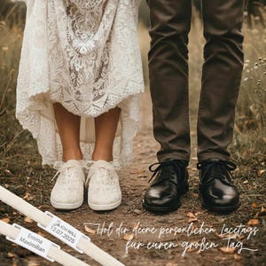 Può includere: Scena di matrimonio con una sposa in abito di pizzo e uno sposo in pantaloni marroni, entrambi con scarpe. L'immagine include etichette per lacci personalizzate con nomi e una data e testo in tedesco.