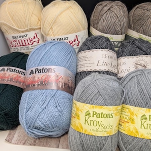 以下が含まれることがあります： 青、緑、グレー、ベージュなど、さまざまな色の糸巻きが揃っています。糸巻きには、パトンズ、バーナット、レイノルズなどのブランド名が付けられています。