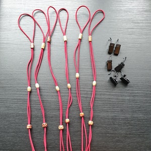 May include: Six red cords with gold and white beads, each with a loop at the top. Six black clips with hooks are also included.