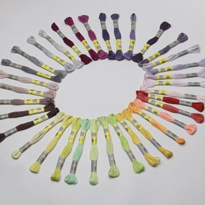 May include: A collection of 36 embroidery floss spools arranged in a circle, showcasing a rainbow of colours from deep purple to light green.