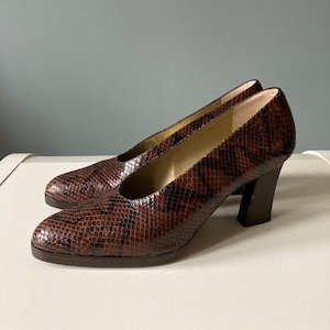Peut inclure: Une paire de chaussures à talons en cuir de serpent brun avec un talon bloc.