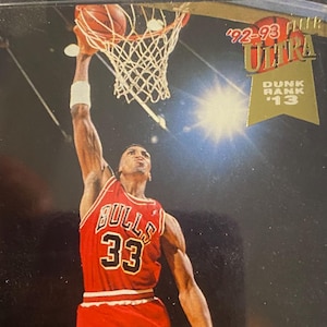 Könnte beinhalten: Eine Basketballkarte von Fleer Ultra aus dem Jahr 1992-93 mit Scottie Pippen von den Chicago Bulls. Die Karte ist von P.A.A.S. mit NM-MT 8 bewertet. Die Karte zeigt Pippen in einem rot-schwarzen Bulls-Trikot, wie er einen Basketball dunkt. Die Karte hat einen blauen und grünen Rand mit dem Text "Scottie Pippen" und "Chicago Bulls F".