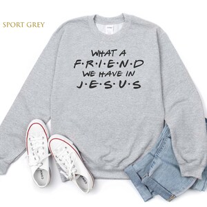 Pu&ograve; includere: Una felpa grigia con la scritta "WHAT A F.R.I.E.N.D WE HAVE IN J.E.S.U.S" stampata su di essa.