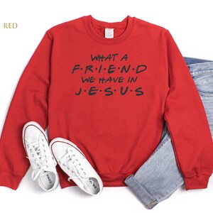 Pu&ograve; includere: Felpa rossa con il testo "WHAT A F.R.I.E.N.D WE HAVE IN J.E.S.U.S" in lettere nere.
