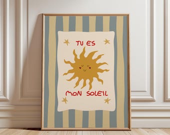 May include: A framed wall art print featuring a central cream-colored rectangle with a mustard yellow sun illustration and the red text TU ES MON SOLEIL. The background consists of vertical stripes in muted blue-gray and tan, with four small stars.