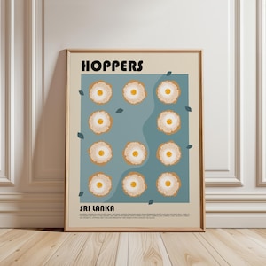May include: A framed poster featuring the text HOPPERS and SRI LANKA with a grid of eleven illustrations of egg hoppers on a blue background. The hoppers are round, tan, and textured with a central yellow yolk. Small dark leaves are scattered around.