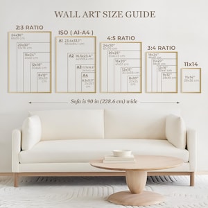 May include: A wall art size guide chart displaying various frame dimensions in inches and centimeters, categorized by ratios including 2:3, ISO A1-A4, 4:5, 3:4, and 11x14. The chart is positioned above a cream-colored sofa that is 90 inches wide.