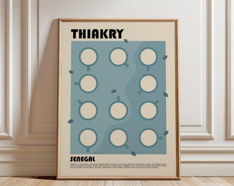 May include: A framed wall art print with a beige background featuring the text THIAKRY at the top and SENEGAL at the bottom. The center displays a blue rectangular graphic containing eleven circular bowls filled with a speckled beige substance.