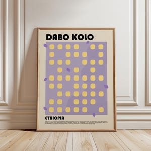 Peut inclure: Une affiche encadrée sur fond beige avec le texte DABO KOLO et ETHIOPIA en noir. Un rectangle violet central contient une grille de petits carrés jaunes et des formes de feuilles violettes éparpillées. Un petit texte noir est présent.