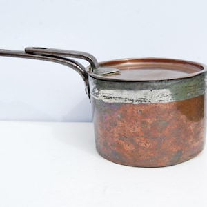 May include: A vintage copper pot with a lid and two handles. The pot has a patina and is in good condition.