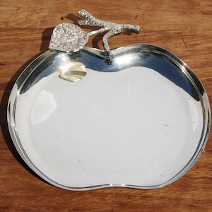 Może przedstawiać: Srebrna, jabłkowata tacka do serwowania z detalicznym wzorem liścia i łodygi.