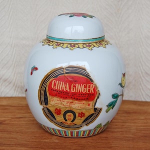 Może przedstawiać: Biały porcelanowy słoik na imbir z czerwonym, żółtym i zielonym wzorem kwiatowym. Słoik ma etykietę z napisem "True China Ginger Preserving Co. Est. 1948 Ltd. Young Stem Ginger"