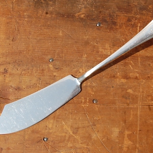 May include: A silver butter knife with a rounded handle and a slightly curved blade.