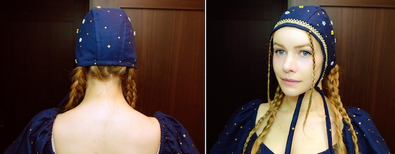 May include: A navy blue cap with gold and white star and flower accents. The cap has a gold trim and is part of a medieval-style costume. The cap is worn with a matching navy blue top with gold star accents.