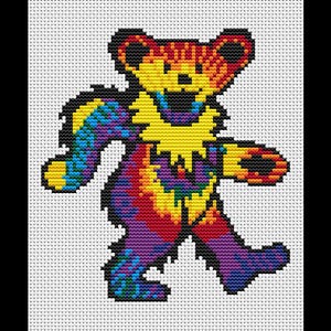 May include: A cross-stitch pattern on white fabric featuring a dancing bear character. The bear is filled with a vibrant, multi-colored tie-dye effect in shades of yellow, red, purple, blue, and green, outlined in a thick black stitch.