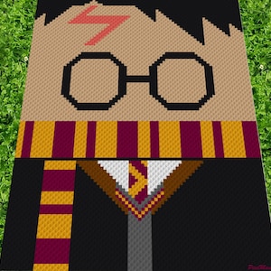 Könnte beinhalten: Ein Häkelmuster von Harry Potter mit einer Blitznarbe auf der Stirn, der eine runde Brille, einen schwarzen Umhang und einen Gryffindor-Schal trägt.