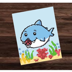 May include: A pixelated illustration of a cartoon shark with a light blue body, white belly, and open mouth. The shark is set against a light blue background with pixelated coral, seaweed, and a crab.