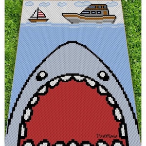 May include: A pixelated design of a shark's open mouth, with a red interior and white teeth. Above the shark, a sailboat and a motorboat are shown on a blue background, with a green border. The design includes the text "PixelMaria".
