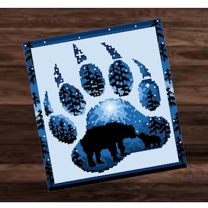 Op de afbeelding: Een blauwe en witte pootafdruk met een silhouet van een beer erin. De pootafdruk is gemaakt van een bos scène met bomen en sterren.