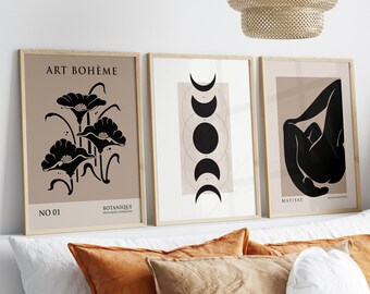 May include: Three framed art prints with a minimalist aesthetic. The prints feature black and white illustrations on a light brown background. The first print features a floral design with the text "ART BOHEME" and "NO 01 BOTANIQUE". The second print features a moon phase design. The third print features a stylized human figure with the text "MATISSE".