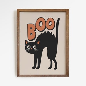 May include: A black cat with orange eyes is silhouetted against a beige background. The word "BOO" is written in orange letters above the cat.