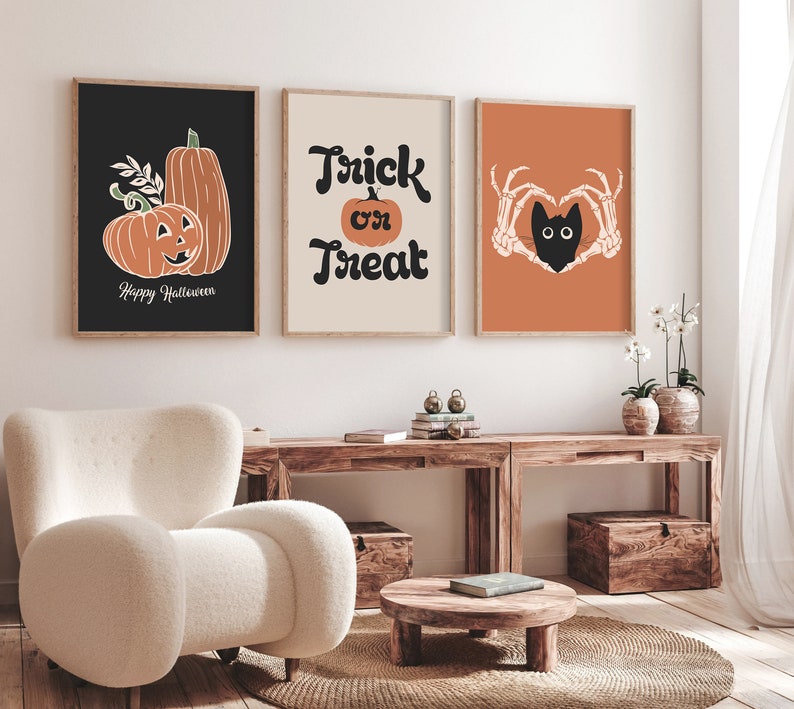 May include: Three framed Halloween-themed art prints. The first features orange pumpkins on a black background with the text "Happy Halloween." The second says "Trick or Treat" with a pumpkin. The third shows a black cat in a heart made of skeleton hands on an orange background.