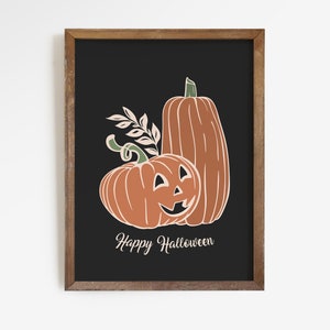 May include: A framed art print featuring two orange pumpkins with white outlines and green stems against a black background. One pumpkin has a carved jack-o'-lantern face. The text "Happy Halloween" is below the pumpkins.
