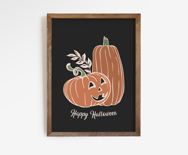 May include: A framed art print featuring two orange pumpkins with white outlines and green stems against a black background. One pumpkin has a carved jack-o'-lantern face. The text "Happy Halloween" is below the pumpkins.