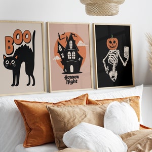 May include: Three Halloween-themed prints in wooden frames. The first print features a black cat with the word "BOO" above it. The second print features a silhouette of a haunted house with the text "Halloween Night". The third print features a skeleton with a pumpkin head taking a selfie.