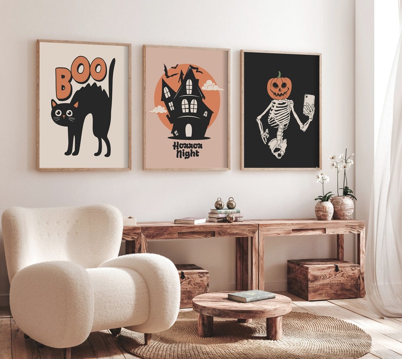 May include: Three Halloween-themed prints with black frames. The first print features a black cat with the word "BOO" above it. The second print features a black silhouette of a house with the words "Horror Night" below it. The third print features a skeleton with a pumpkin head taking a selfie.