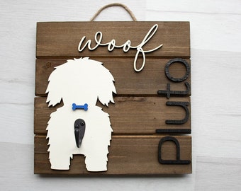 May include: Wooden sign with a white silhouette of a dog with a blue bone and the words "woof" and "Pluto" in black lettering.