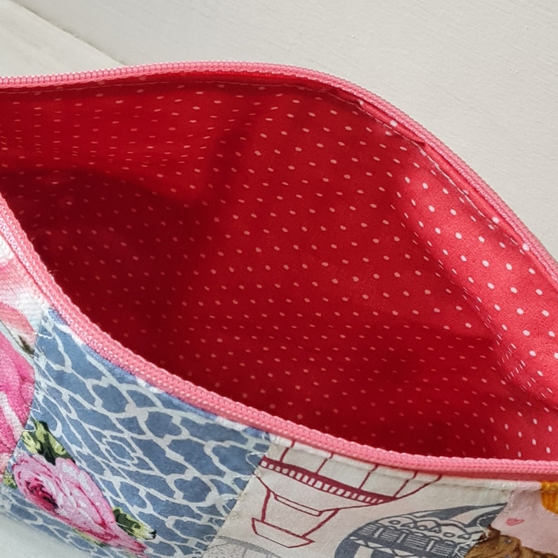Peut inclure: Une pochette zipp&eacute;e en patchwork rose et bleu avec une doublure &agrave; pois rouges. La pochette pr&eacute;sente un motif floral avec des roses et un motif g&eacute;om&eacute;trique.