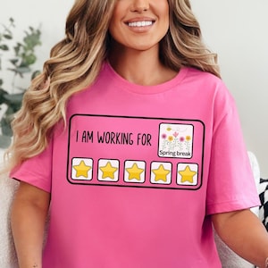 May include: Pink t-shirt with the text "I am working for Spring Break" and five yellow stars.