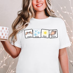 May include: White t-shirt with a graphic of four squares. Each square has a different image and text. The first square shows a hand gesture with the text "more". The second square shows snowflakes with the text "snow". The third square shows a sun with the text "days". The fourth square shows a hand gesture with the text "please".