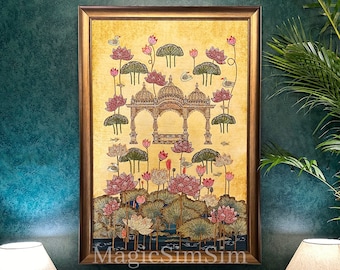 May include: A framed painting depicting a yellow and gold landscape with a pink and white lotus flower design. The painting features a small, ornate structure in the center, surrounded by lotus flowers and leaves. The painting is framed in a gold frame.