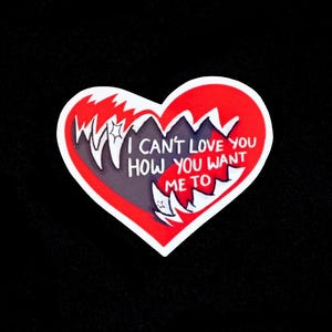 Könnte beinhalten: Ein herzförmiger Aufkleber mit rotem Rand und roter Innenseite. Das Herz hat ein gezacktes, zerrissenes Design mit den Worten "I CAN'T LOVE YOU HOW YOU WANT ME TO" in weißem Text.