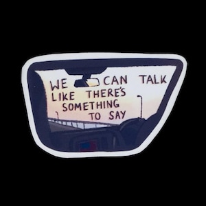 May include: A sticker featuring a car's rearview mirror with a highway scene. The text in the mirror reads, "WE LIKE THERE'S SOMETHING TO SAY." The sticker has a white border and is set against a black background.