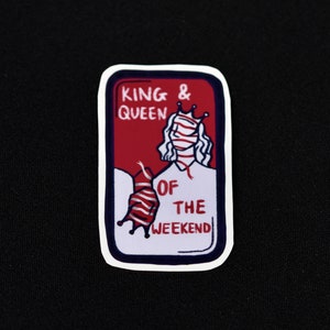 Könnte beinhalten: Ein roter und weißer Aufkleber mit dem Text "King & Queen of the Weekend" und einer Cartoon-Illustration einer Person mit Krone und Schal.