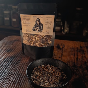 May include: A black pouch of "Herbal Coffee" with a skull graphic and ingredient list, next to a small black bowl filled with the herbal blend. The label reads "Haints and Hollers Apothecary."