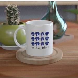 May include: White ceramic mug featuring a blue sheep design and the text "12, Baa Blues".