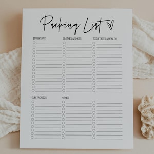 May include: A white packing list with the title "Packing List" in a handwritten font. The list is divided into sections for important items, clothes & shoes, toiletries & health, electronics, and other. A decorative coral and fabric are in the background.