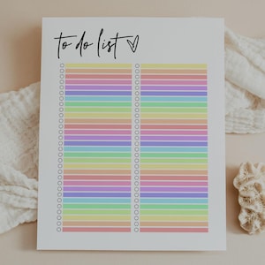 May include: A white to-do list notepad with a rainbow-colored striped design. The words "to do list" are written in black script at the top, with a small heart symbol. The notepad has a series of small circles along the left and right sides.